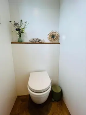 a bathroom with a white toilet with a shelf above it at Surla houseboat 
