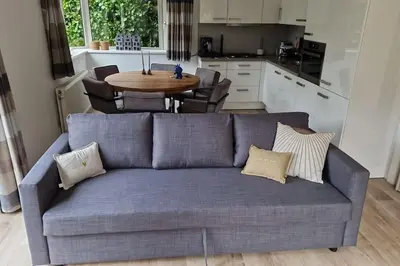 a blue couch in a kitchen with a table at Luxe chalet met airco bij bos en zwemwater in Hoevelaken
