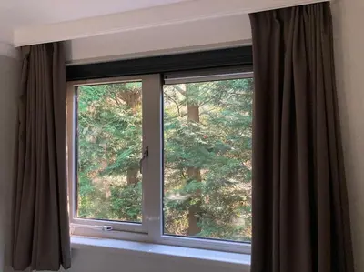 a window with brown curtains in a room at Luxe chalet met airco bij bos en zwemwater in Hoevelaken