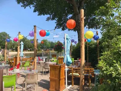 a patio with tables and chairs and colorful lanterns at Luxe chalet met airco bij bos en zwemwater in Hoevelaken