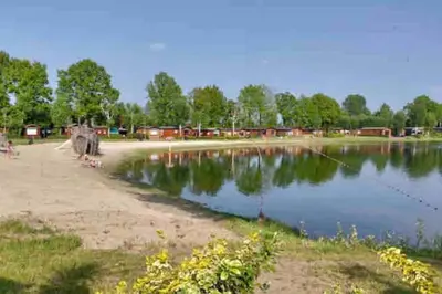 a body of water with houses in the background at Luxe chalet met airco bij bos en zwemwater in Hoevelaken