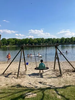 a group of people playing on a swing set on the beach at Luxe chalet met airco bij bos en zwemwater in Hoevelaken