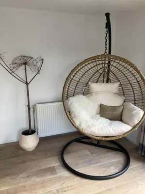 a room with a rattan chair with pillows at Luxe chalet met airco bij bos en zwemwater in Hoevelaken