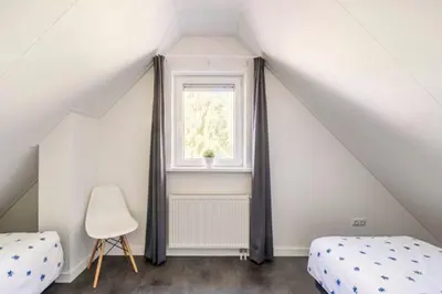 a attic bedroom with two beds and a window at Modern Luxury villa in Zeewolde