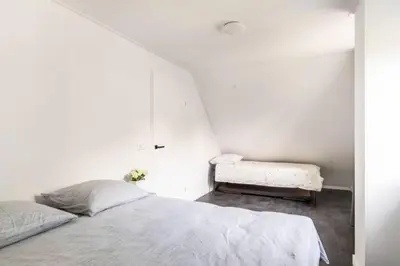 a white bedroom with a bed and a bench at Modern Luxury villa in Zeewolde