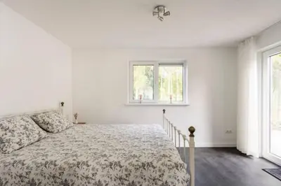 a white bedroom with a bed and two windows at Modern Luxury villa in Zeewolde