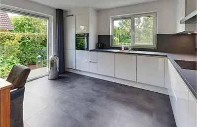 a kitchen with white cabinets and a large window at Modern Luxury villa in Zeewolde