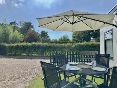a table with an umbrella on a patio at Vakantiehuis 't Hofje nabij dorpscentrum en strand in Castricum