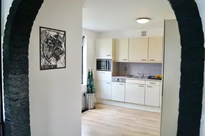 an open kitchen with white cabinets and a table at Vakantiehuis 't Hofje nabij dorpscentrum en strand in Castricum