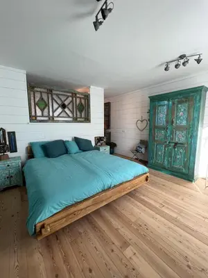 a bedroom with a large bed with blue pillows at The Coast Beach House in Egmond aan Zee