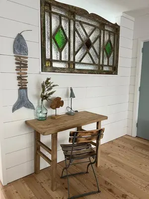 a wooden table and chair in a room with a window at The Coast Beach House in Egmond aan Zee