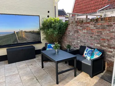 a patio with a table and chairs and a brick wall at The Coast Beach House in Egmond aan Zee