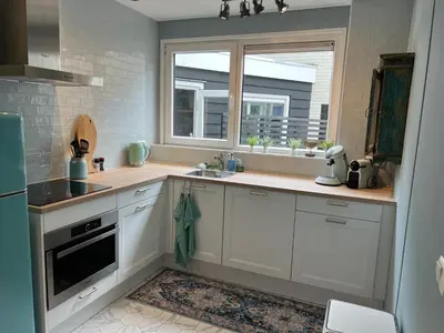 a kitchen with white cabinets and a sink and a window at The Coast Beach House in Egmond aan Zee