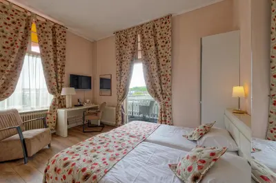 a bedroom with a bed and a desk and windows at Mare Sanat in Wijk aan Zee