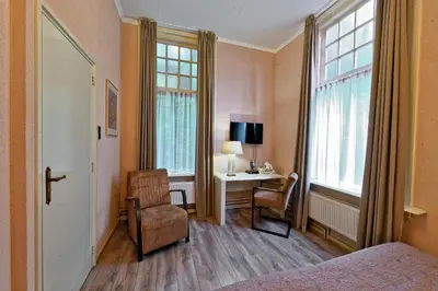a bedroom with a bed and a desk and a window at Mare Sanat in Wijk aan Zee