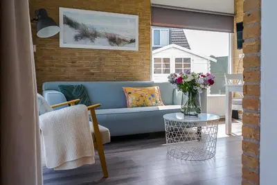a living room with a blue couch and a table at -Casa Nova- nabij het meer, duinen en restaurants in Noordwijkerhout