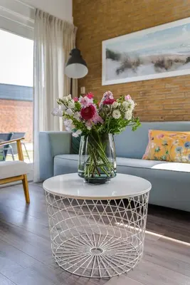 a vase of flowers on a table in a living room at -Casa Nova- nabij het meer, duinen en restaurants in Noordwijkerhout