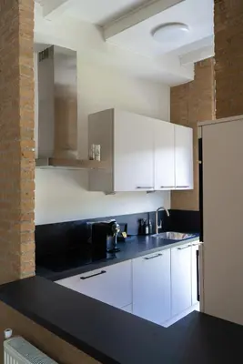 a kitchen with white cabinets and a black counter top at -Casa Nova- nabij het meer, duinen en restaurants in Noordwijkerhout