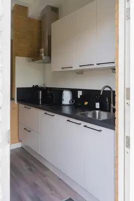 a kitchen with white cabinets and a sink at -Casa Nova- nabij het meer, duinen en restaurants in Noordwijkerhout