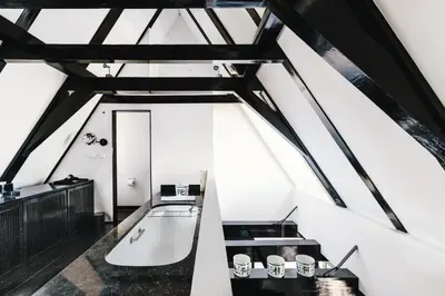 an attic room with a tub and a sink at The Dylan Amsterdam - The Leading Hotels of the World in Amsterdam