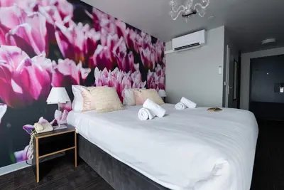 a bedroom with a large bed with pink flowers on the wall at Multatuli Hotel in Amsterdam