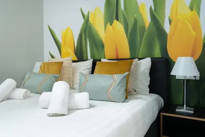 a white bed with pillows and a painting of flowers at Multatuli Hotel in Amsterdam