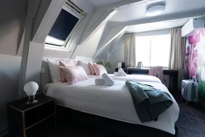 a bedroom with a large white bed with pink pillows at Multatuli Hotel in Amsterdam