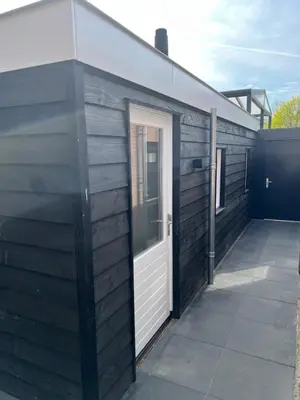 a wooden building with a white door on it at Luxe woning ‘BARNS’ Castricum aan Zee + airco + parkeren in Castricum