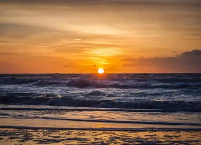 a sunset on the beach with the ocean at Luxe woning ‘BARNS’ Castricum aan Zee + airco + parkeren in Castricum