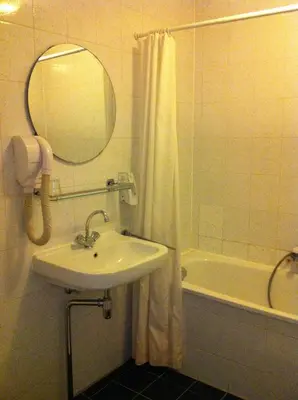 a bathroom with a sink and a tub and a mirror at Delta Hotel City Center in Amsterdam
