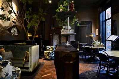 a living room with chairs and tables and a fireplace at Boutique hotel Villa Trompenberg in Hilversum
