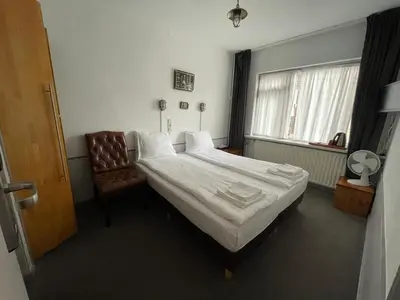 a hotel room with a bed and a chair at Amadeus Hotel in Haarlem