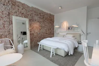 a bedroom with a white bed and a brick wall at Mother Goose Hotel in Utrecht