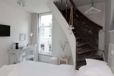 a bedroom with a staircase and a bed and a desk at Mother Goose Hotel in Utrecht
