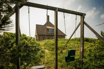 a house on top of a hill with a swing at Villa de Duintop in Bergen aan Zee
