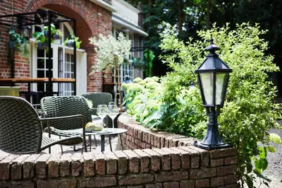 a street light on a brick wall with chairs and tables at Kasteel Kerckebosch in Zeist