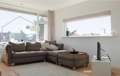 a living room with a brown couch and a television at Duinzicht 2 in Bergen aan Zee