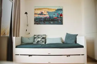 a white bed with blue pillows on top of it at Duinzicht 2 in Bergen aan Zee