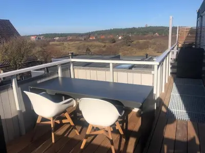 a black table and two white chairs on a balcony at Duinzicht 2 in Bergen aan Zee