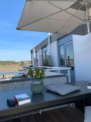 a table with a vase of flowers on a deck at Duinzicht 2 in Bergen aan Zee