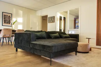 a living room with a black couch and a table at The marine apartment near Amsterdam by Weltevreden Experience in Kortenhoef