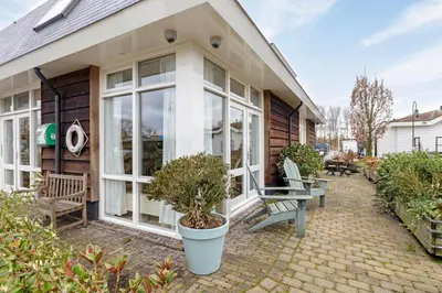 a house with a patio with chairs and trees at The marine apartment near Amsterdam by Weltevreden Experience in Kortenhoef
