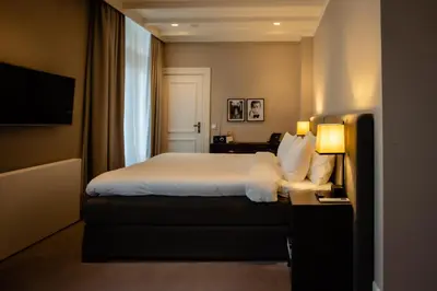 a hotel room with a bed and a television at Villa de Duinen - Adults Only in Noordwijk aan Zee
