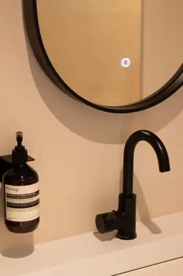 a bottle of soap sitting on a sink next to a mirror at B&B Midtown Amsterdam suites in Amsterdam