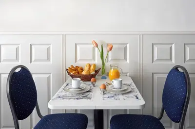 a white table with two chairs and a bowl of fruit at Hotel D'Amsterdam Leidsesquare in Amsterdam