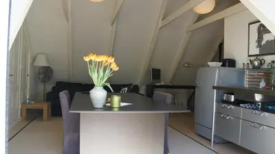 a kitchen with a table with a vase of flowers on it at Room One-Twenty-One in Naarden