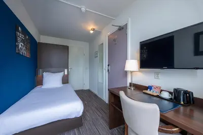 a hotel room with a bed and a desk with a computer at Amrâth Hotel Media Park Hilversum in Hilversum