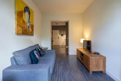 a living room with a blue couch and a tv at Amrâth Hotel Media Park Hilversum in Hilversum