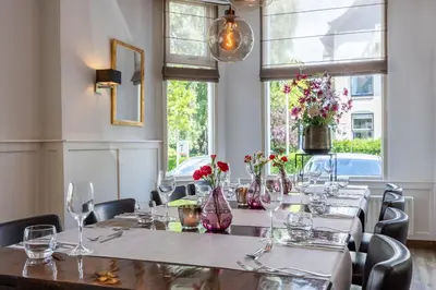 a dining room with a long table with flowers in vases at Amrâth Hotel Media Park Hilversum in Hilversum