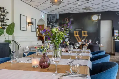 a long table with glasses and flowers in a restaurant at Amrâth Hotel Media Park Hilversum in Hilversum